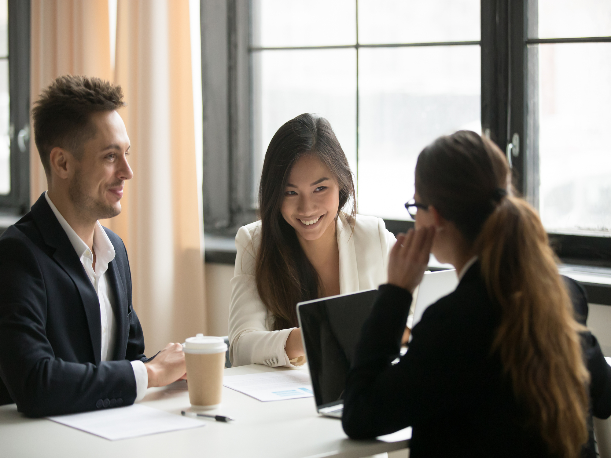 Laughing Asian businesswoman talking with business partners during corporate negotiations about plans, strategies and company merging. Concept of cooperation, interview, collaboration and partnership.